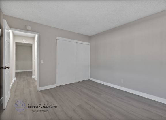 A room with a door on the left and a white closet on the right.
