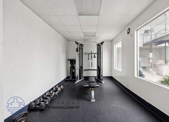 A gym with a row of dumbbells and a weight rack.