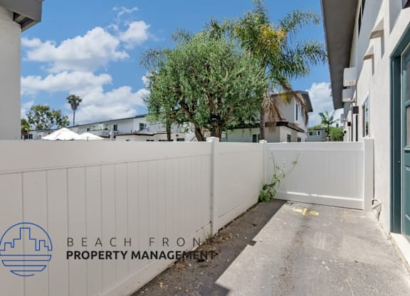a white privacy fence in front of a house with a sidewalk