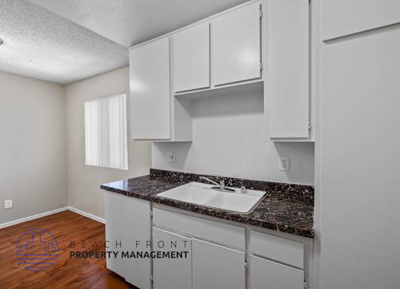 A kitchen with white cabinets and a granite countertop.