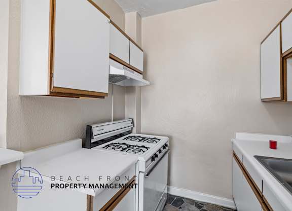 A kitchen with white cabinets and a stove top oven.