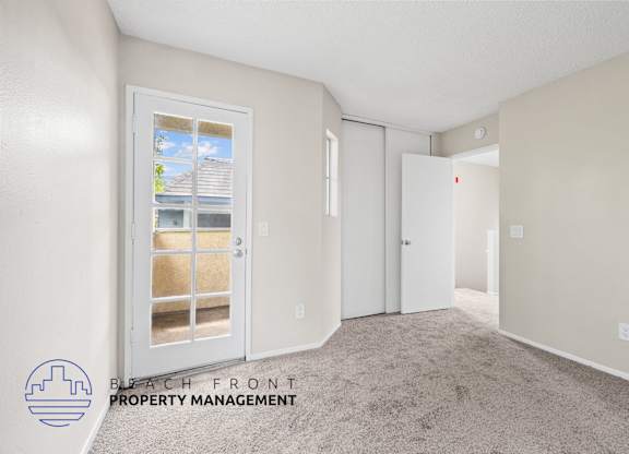 A room with a carpeted floor and a window with a view of a house.