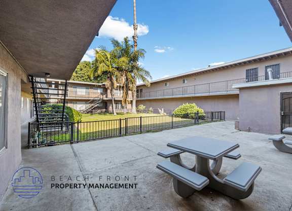 A patio with a table and chairs is shown with the logo of Beach Front Property Management.