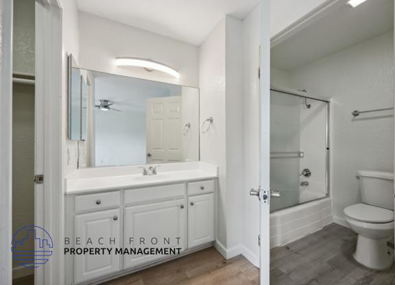 A bathroom with a white toilet and a white sink with a mirror above it.