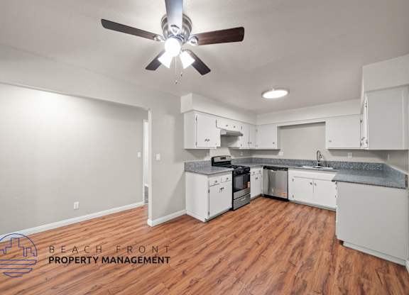 A kitchen with a ceiling fan and wooden floors.