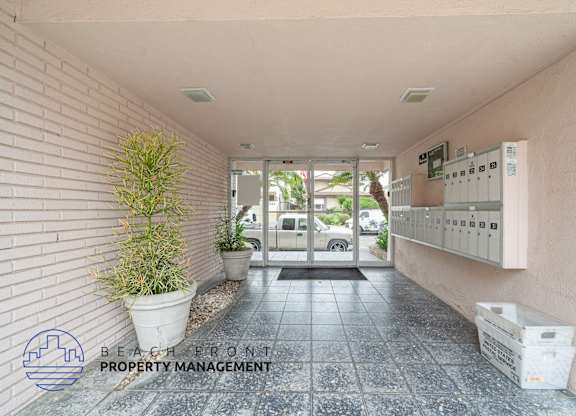 A hallway with a plant and a sign for Beach Front Property Management.