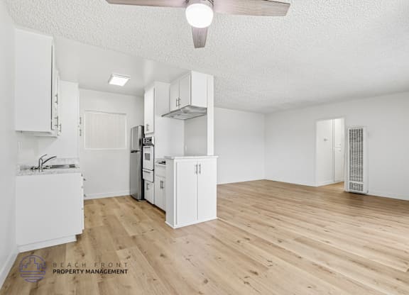 A spacious kitchen with white cabinets and a wooden floor.
