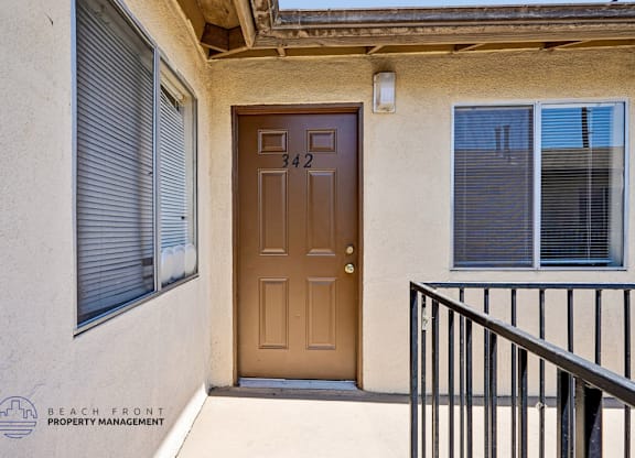 A brown door with the number 342 on it is on the front of a house.