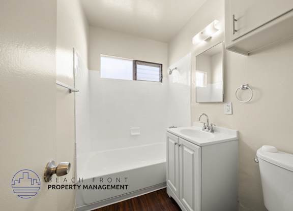 A white bathroom with a sink, mirror, and bathtub.