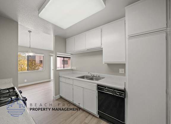 a white kitchen with white cabinets and a black dishwasher