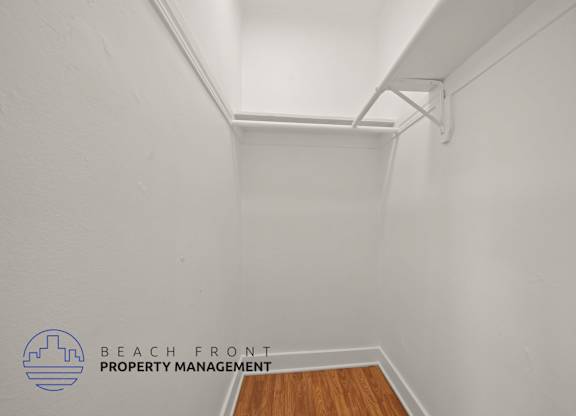 A white room with a wooden floor and a white ceiling with a beam.