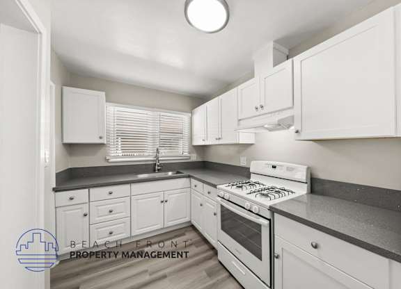 A kitchen with white cabinets and a stove top oven.