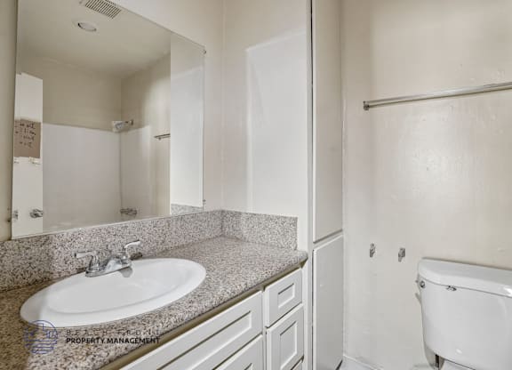 A white bathroom with a sink, toilet, and a towel rack.
