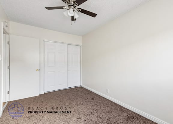 A room with a ceiling fan and a carpeted floor.
