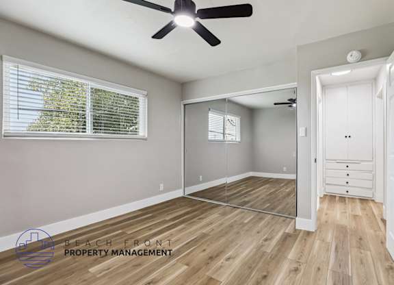 A room with a ceiling fan and wooden flooring.