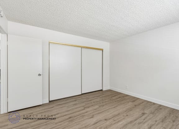 A room with a white door and a white closet with a gold trimmed door.