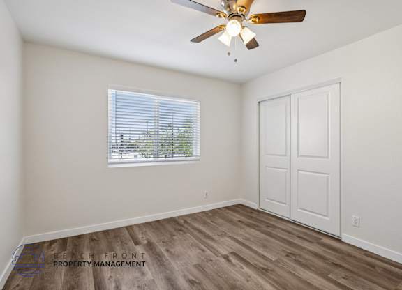 A room with a ceiling fan and a window with blinds.