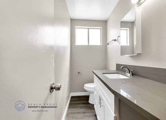 A bathroom with a toilet, sink, and mirror.
