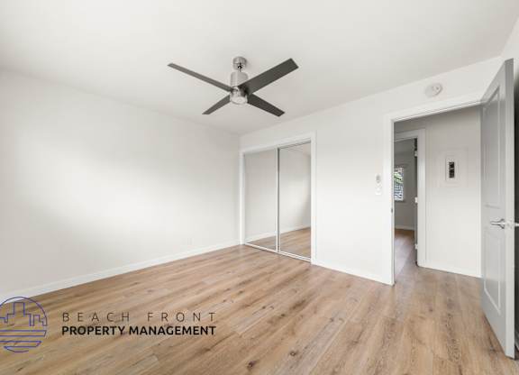 A room with a ceiling fan and a logo for Beach Front Property Management.