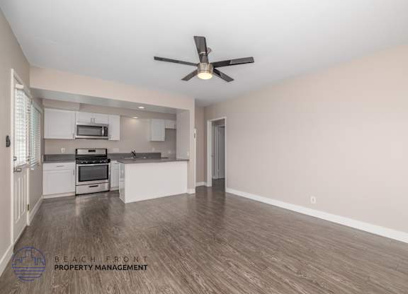 A spacious room with a fan and wooden flooring.