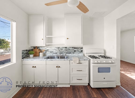 A kitchen with white cabinets and a wooden floor.