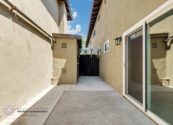 A narrow alleyway between two buildings with a clear blue sky above.