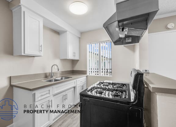 a kitchen with white cabinets and a stove and a sink
