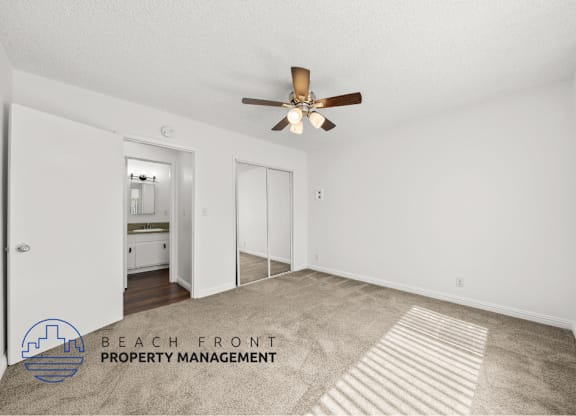 view of a large bedroom with mirror doors for the closet and leads into the bathroom