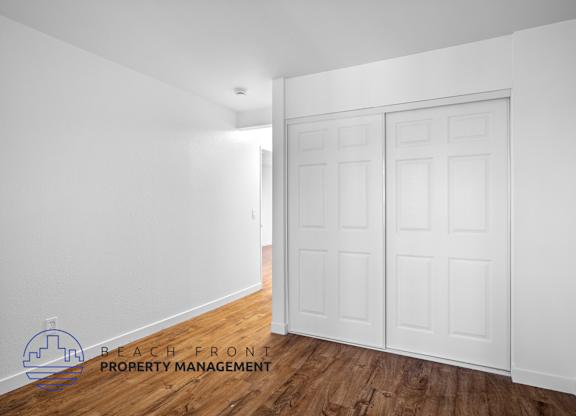 A white room with a wooden floor and a white door.