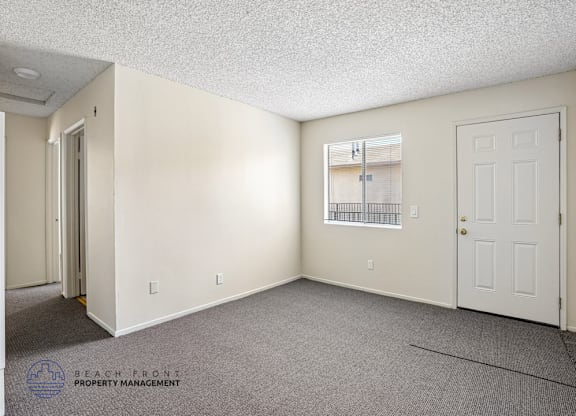 A sparsely furnished room with a window and a door.