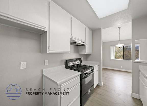 a kitchen with white cabinets and a stove and a window