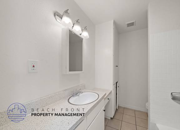 A bathroom with a sink, mirror, and shower.