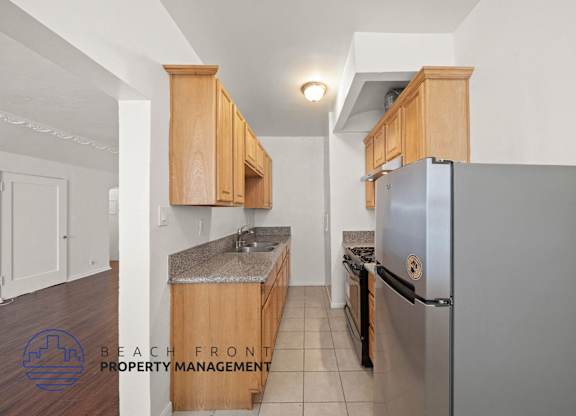 A kitchen with wooden cabinets and a stainless steel refrigerator.