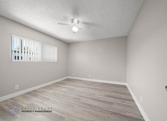 A room with a ceiling fan and a window with blinds.