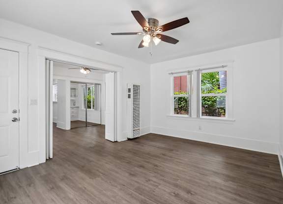 A room with a ceiling fan and wooden flooring.