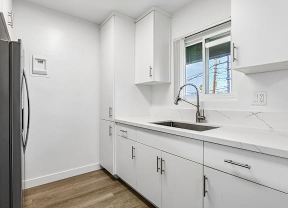 A kitchen with white cabinets and a black refrigerator.