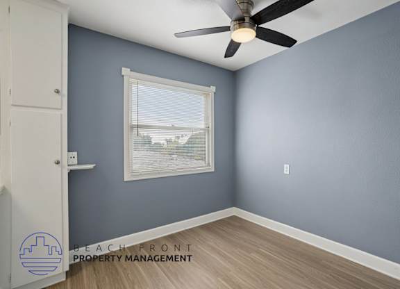 A room with a ceiling fan and a window with blinds.