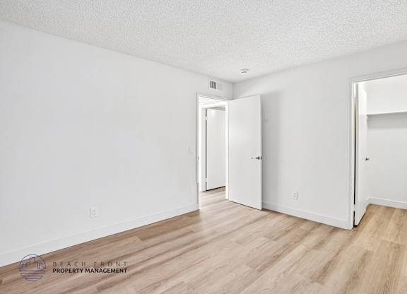 A white room with wooden floors and two doors.