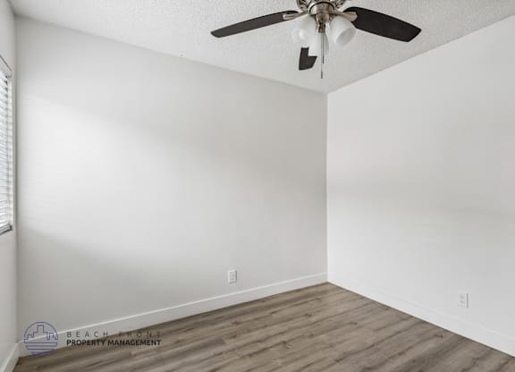 A room with a ceiling fan and wooden flooring.