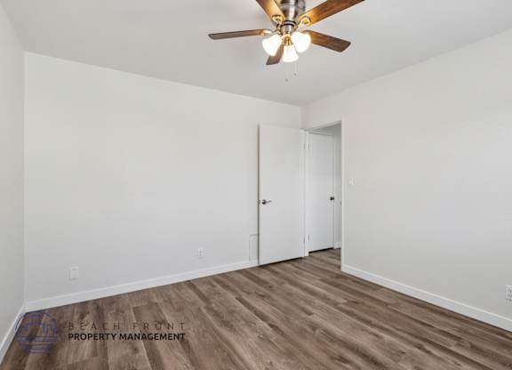 A room with a ceiling fan and wooden flooring.