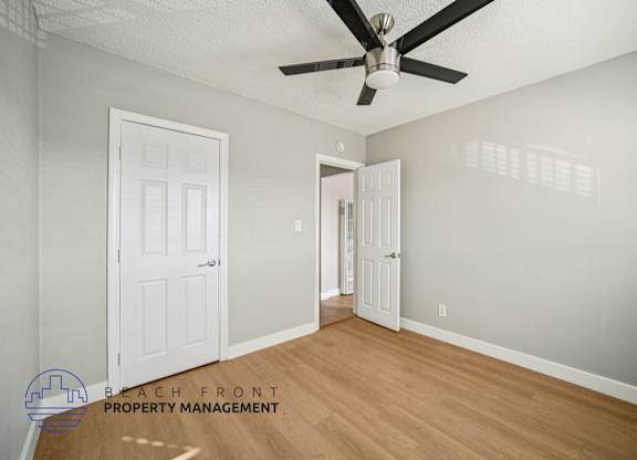 A room with a ceiling fan and two doors.