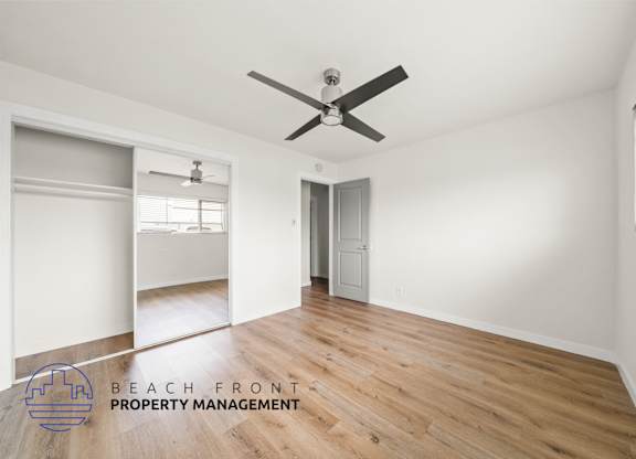 A spacious room with a ceiling fan and wooden flooring.