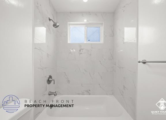 a white bathroom with a tub and a shower and a window