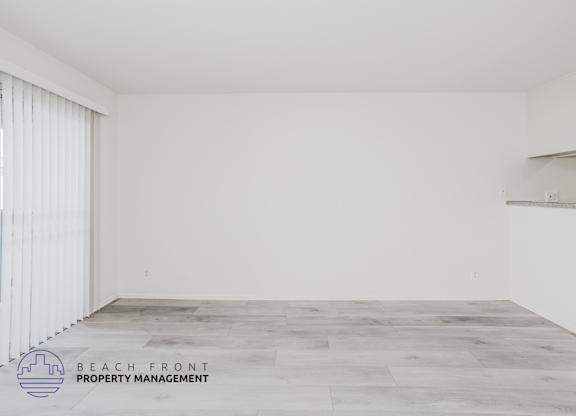 A spacious room with a wooden floor and white walls.