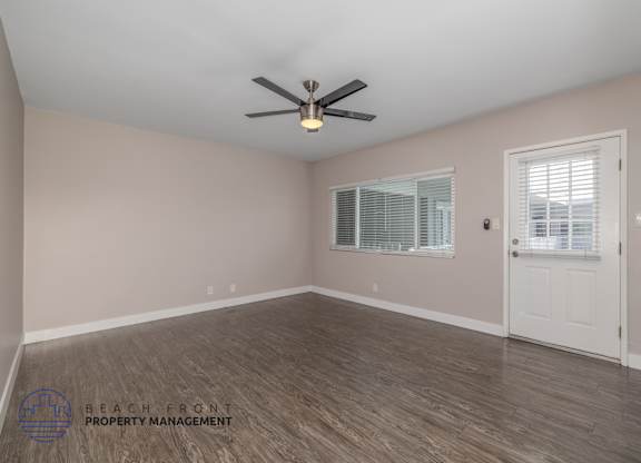 A room with a ceiling fan and wooden flooring.