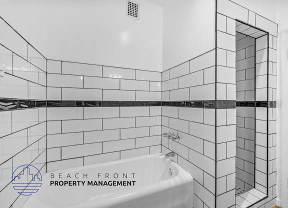 a white tiled bathroom with a tub and a shower