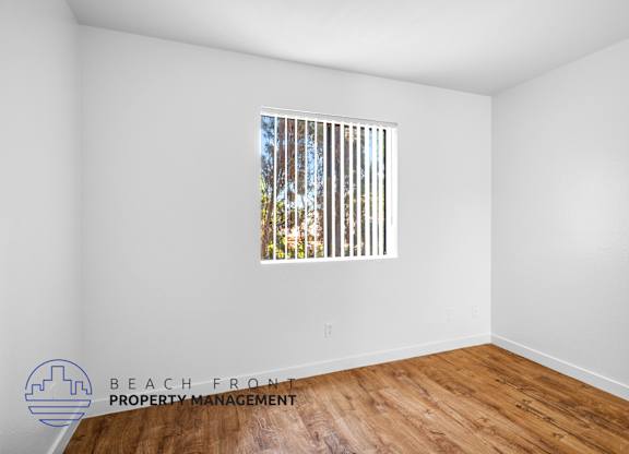 the living room of the new home with wood flooring and a window