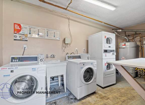 A laundry room with washers and dryers and a sign that says Beauty Front Property Management.