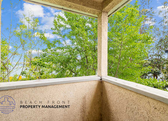 A window with a view of trees and a blue sky.