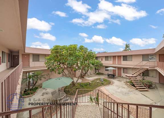 A courtyard with a tree and a table surrounded by buildings.